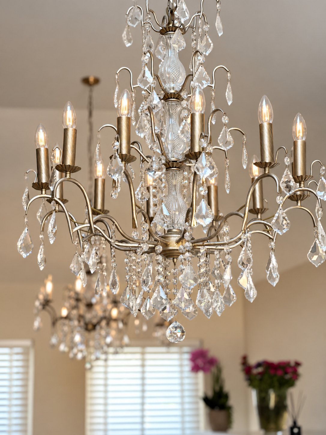 Ornate brass chandelier with cut glass crystals and candle-style bulbs glowing in a warm interior.