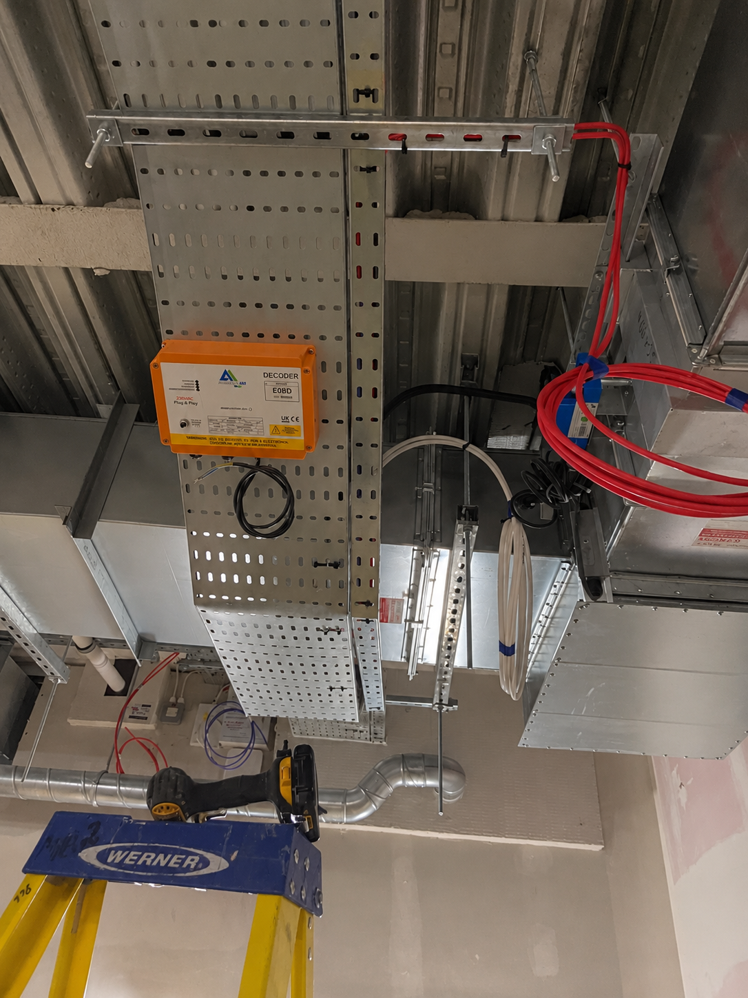 Orange control box fixed to a perforated cable tray with black, white and red cables, beneath a metal deck ceiling.