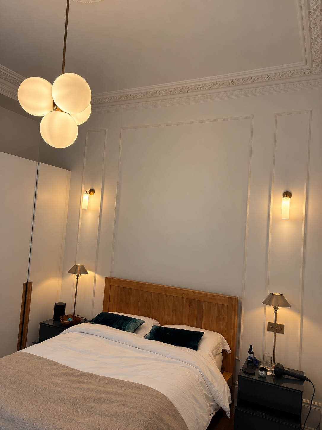 Classic bedroom with a frosted glass globe pendant light and two brass wall lights either side of the bed.