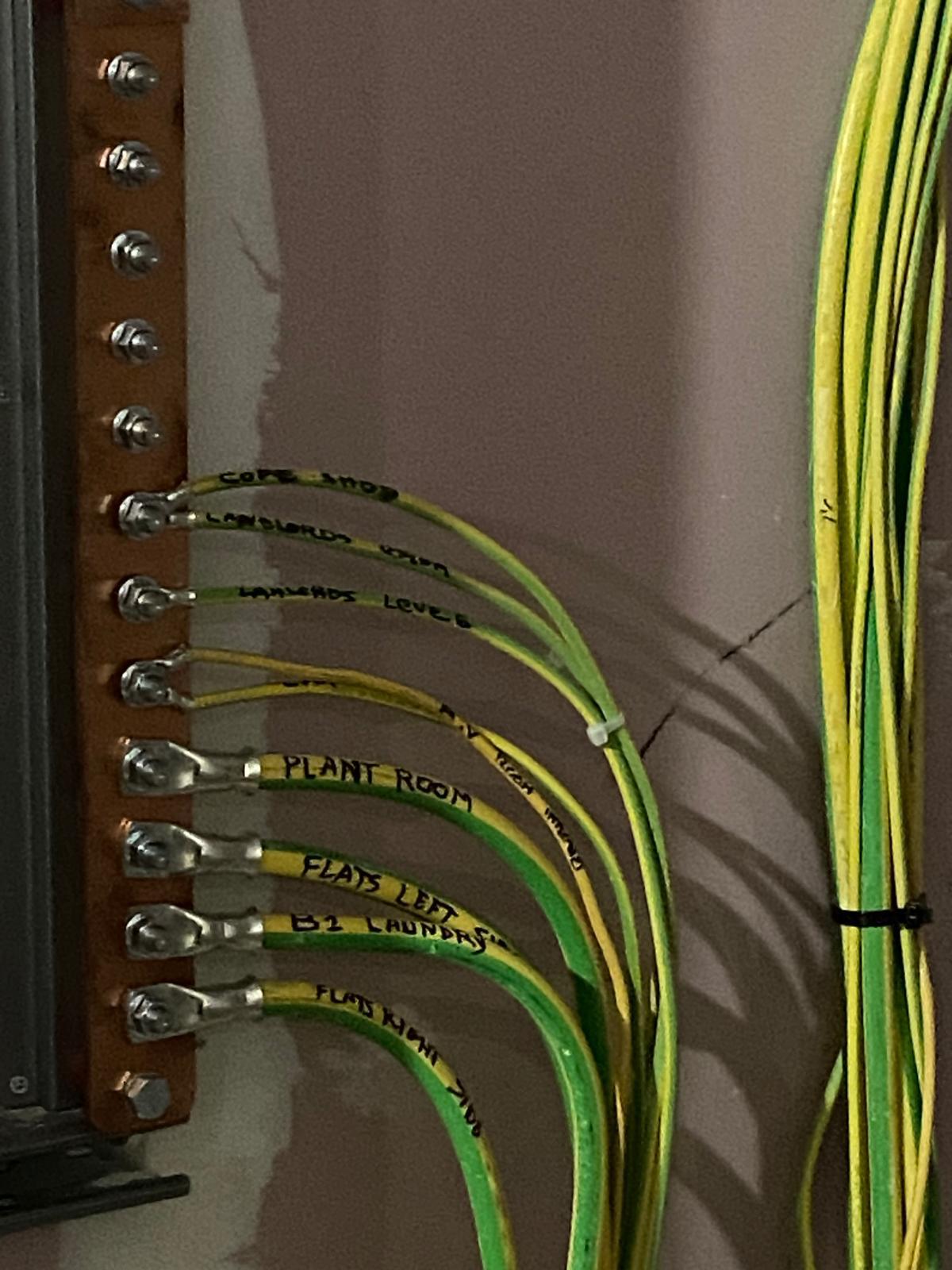 Copper busbar with a row of labelled green-and-yellow earth wires connected to it.